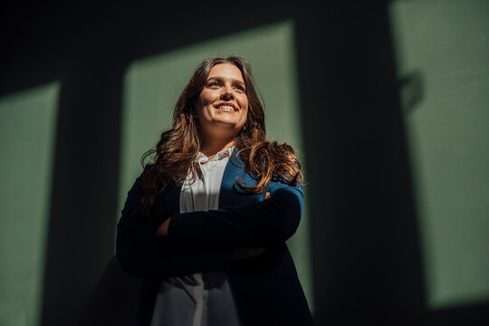 Confident businesswoman smiling indoors with arms crossed