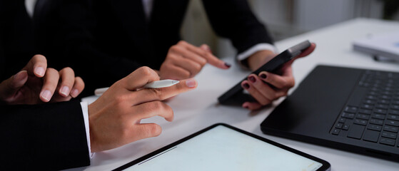 Two colleagues discussing data with smart phone and new modern computer laptop on desk table. Close up business team concept.