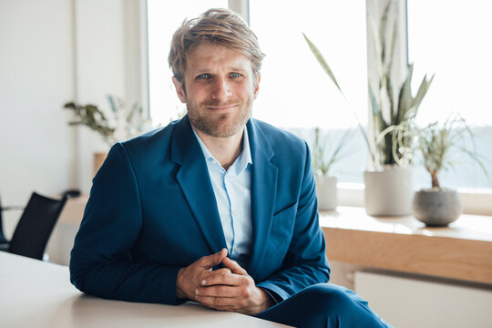 Confident businessman in blue suit smiling in modern office