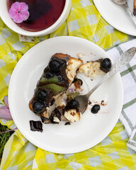 Slice of cheesecake on plate with chocolate, kiwi, blueberries, pink flowers, stylish dessert scene