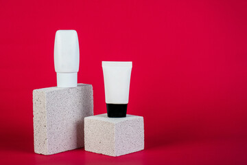 Plastic white tube for cream or lotion. Skin care or sunscreen cosmetic with stylish props on red background.