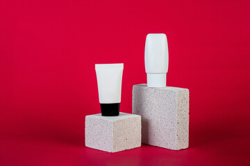 Plastic white tube for cream or lotion. Skin care or sunscreen cosmetic with stylish props on red background.