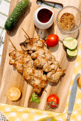 Outdoor picnic with grilled fish kebabs, fresh vegetables on rustic table, sunny summer setting