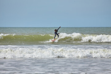A young female surfer gracefully rides the waves on her board along the shores of Essaouira, Morocco