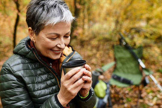 Joyful moments enjoying warm drink while hiking through vibrant autumn forest