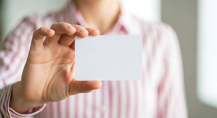 Professional woman in a striped shirt holding a blank white business card mockup for contact