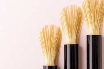 Three makeup brushes with beige bristles on pastel pink background, soft studio lighting, suitable for beauty and makeup tutorials