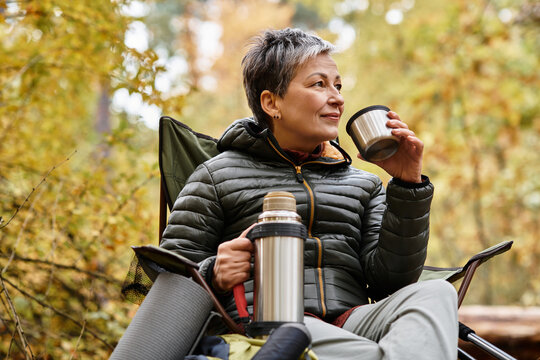 Enjoying a peaceful moment with a warm drink while hiking in a beautiful forest - Powered by Adobe