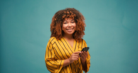 Pretty young woman wearing yellow t-shirt smiles at blue wall