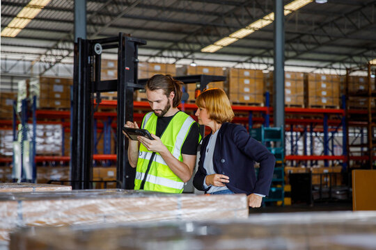 Manager with colleague using tablet PC in warehouse