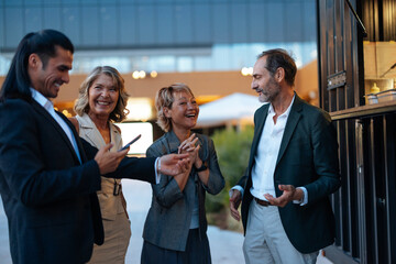Businesspeople laughing and talking during a break outside office