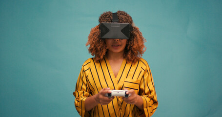Hispanic Latin Woman Playing Game Online at Blue Backdrop. Gamer Female in VR Virtual Reality Goggles Controlling Joystick for Video Game. Leisure Game Cyberpunk Concept