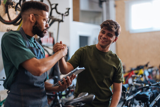 Bicycle mechanics shaking hands after successful bicycle repair
