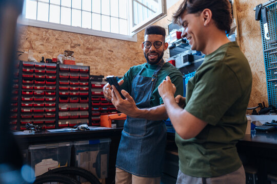 Bicycle mechanics using mobile phone in workshop