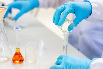 Fototapeta premium A scientist performs a borax detection test in a laboratory using an orange chemical solution inside a volumetric flask. Represents chemical analysis, food safety research in laboratory.