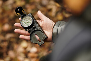 Exploring nature with a compass in the serene forest by a senior woman on a sunny day