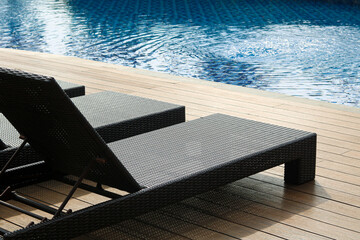 A swimming pool with calm, blue water and stylish lounge chairs on a wooden deck, creating a perfect atmosphere for relaxation.
