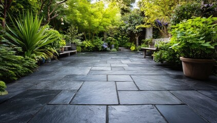 Dark slate patio stones create a pathway through a lush, vibrant garden, flanked by potted plants and benches