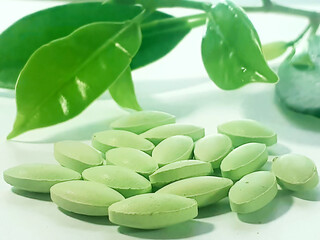 Green Dietary Supplements and Natural Leaves on White Background