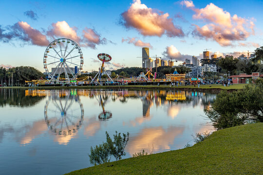 Vibrant Barigui Park in Curitiba, capital and largest city in the state of Parana, featuring a funfair and a ferris wheel against the city skyline. Brazil.