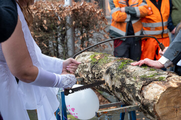 Bride and groom during the traditional sawing of a tree trunk