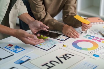 Digital Design Collaboration. Team members discussing mockups and color choices on a tablet.