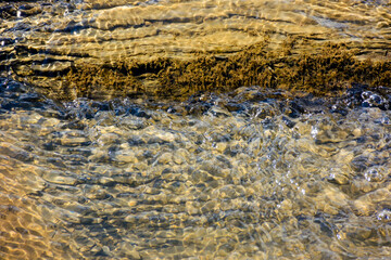 nature texture with stones in the water steam. closeup background of a river shore in autumn