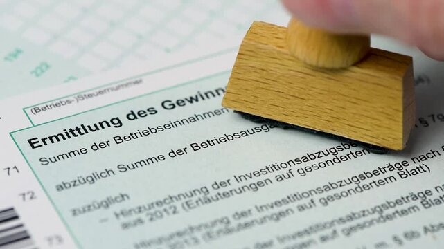 Ein Formular zur Einkommensteuer wird vom Finanzamt mit einem Stempel markiert - FOTOMONTAGE