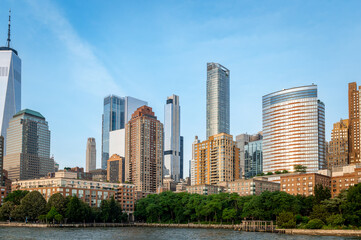 Fototapeta premium Manhattan skyline with tall skyscrapers on clear day. View of Manhattan skyline with tall skyscrapers under clear blue sky in daylight.