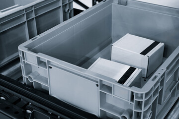 Fototapeta premium Conveyor belt with two empty plastic containers. Gray containers placed on the conveyor belt. Delivery logistics warehouse storage concept.