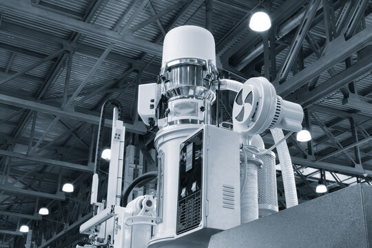 Large industrial PVC extrusion machine against industrial metal roof with lighting.