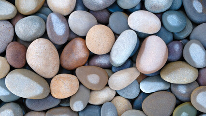 Pebbles stones on seashore as  texture background for design web banner template page. many stones and they are different in color and size, dry stones illuminated by sun.