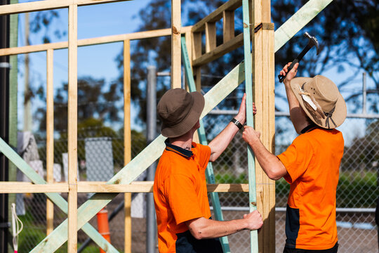 Two trade apprentice workers learning through hands on course building frame of ticket booth