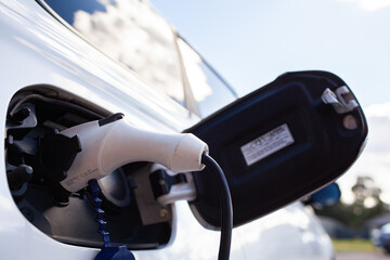 Plugged in Hybrid Electric vehicle car on charge with clouds reflected in windows