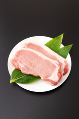 皿に乗った豚ロース肉　黒背景