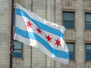 The Chicago city flag waves proudly against a classic stone building, a symbol of civic pride and local identity in Chicago, Illinois, USA.