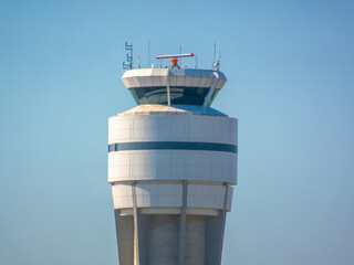 Calgary International Airport control tower stands tall against a clear blue sky, a symbol of aviation command, safety, and modern air traffic control