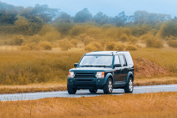 Large rugged SUV driving on quiet asphalt road