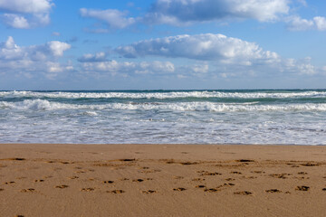 Empty beach with crashing waves and footprints in the sand, travel and vacation concept