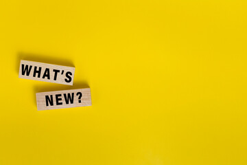 what's new words on wooden blocks isolated on yellow background. copy space