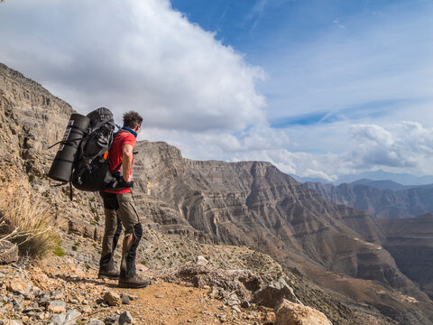 Hiker with backpack overlooking Hajar mountains in Ras Al Khaimah UAE
