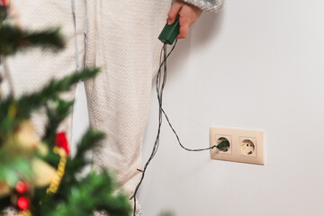 A teenage girl leaning against the wall and as if playing a prank, she has the Christmas lights...