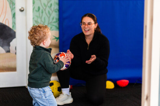 Child and physio doing coordination activity throwing ball in clinic