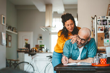 Smiling woman with man preparing financial bills at home
