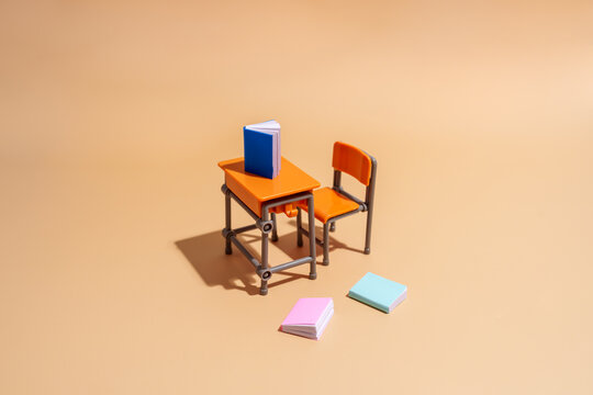 Empty school desk and chair with book on brown background high angle