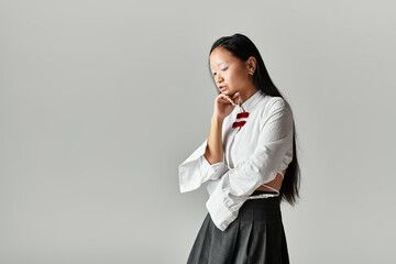 Stylish young woman with blue hair poses thoughtfully in modern grey studio space