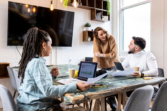 Happy businesswoman with colleagues having discussion in office