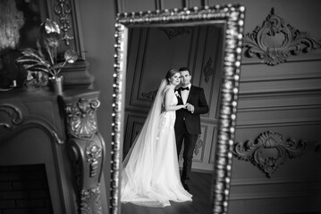 young couple bride and groom in a dark studio with a floor mirror