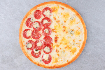 Half Pepperoni and Half Four Cheese Pizza with Mozzarella, Blue Cheese and Golden Crust on Gray Stone Background
