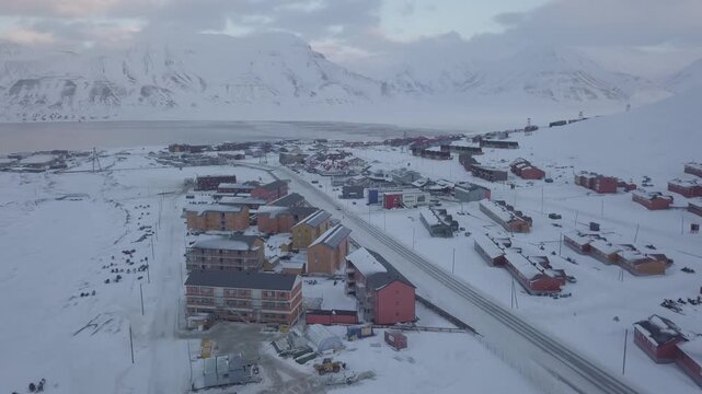 Drone flight. Aerial view of Longyearbyen, Svalbard in winter. Landscape with mountains and colorful houses. Image in D-log without color correction.